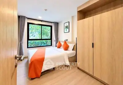 Modern bedroom with large window and wooden wardrobe, featuring bright orange accents.
