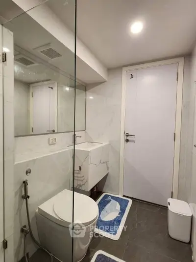 Modern bathroom with sleek design, featuring a glass shower and elegant fixtures.
