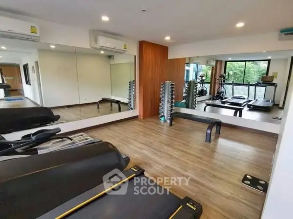 Modern gym with treadmills and mirrored walls in a residential building.