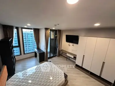 Spacious modern bedroom with large windows and city view, featuring a sleek design and ample storage.