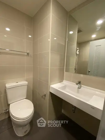 Modern bathroom with sleek fixtures and large mirror in contemporary apartment.