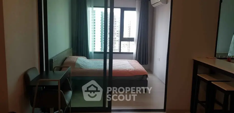 Modern bedroom with large window and glass sliding doors in urban apartment