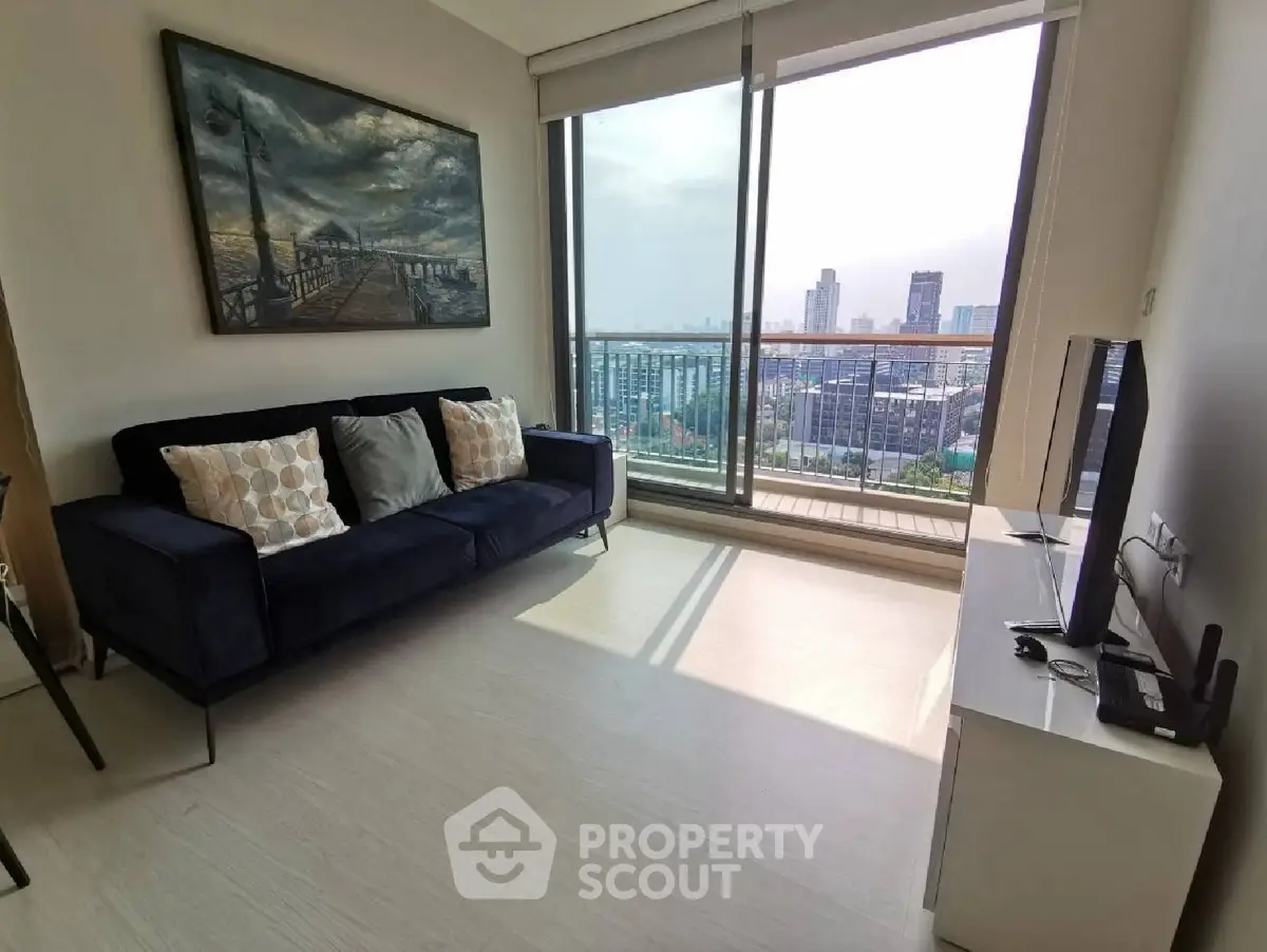 Modern living room with city view, featuring a sleek sofa and large windows for natural light.