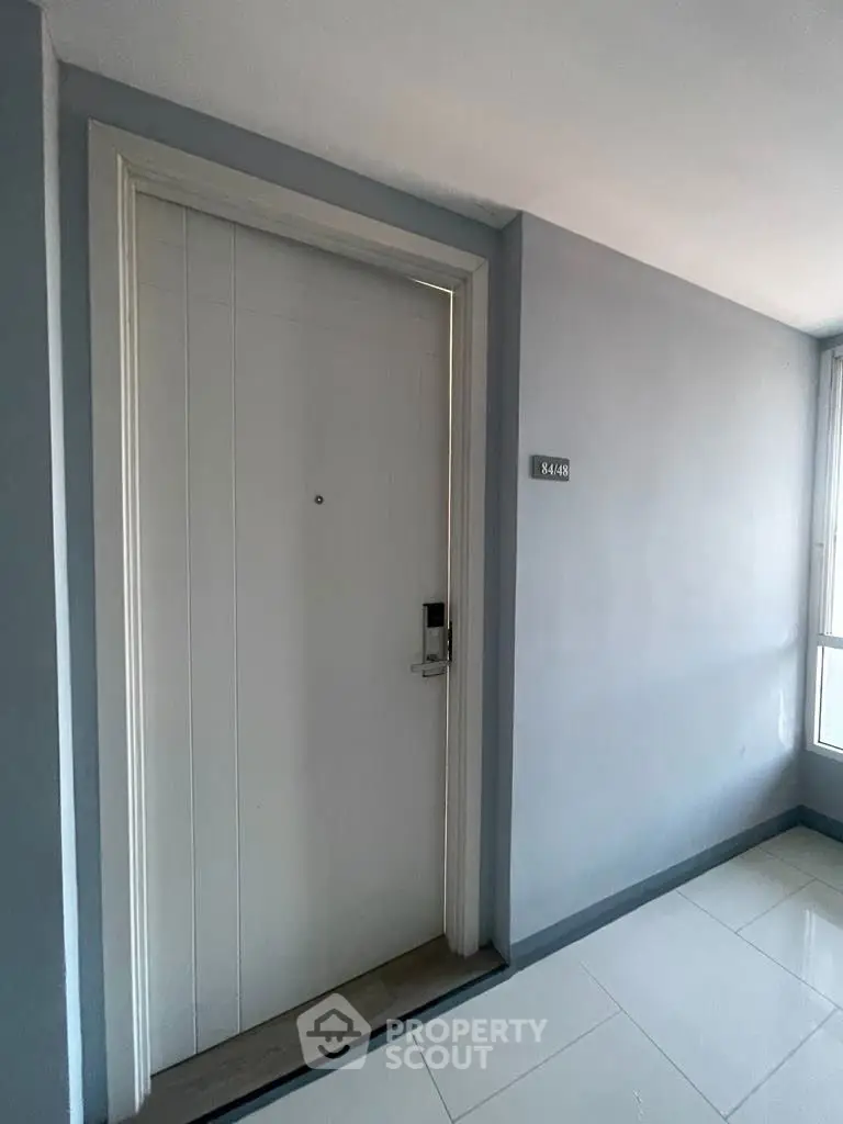 Modern apartment entrance with sleek white door and digital lock