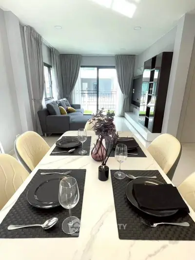 Modern dining area with elegant table setting and cozy living room in open layout apartment.