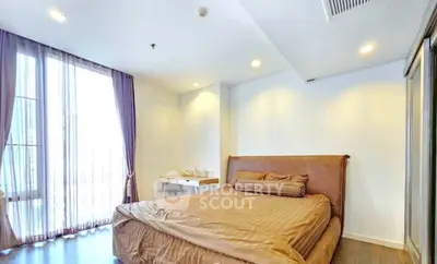 Spacious bedroom with elegant decor and large window offering natural light.