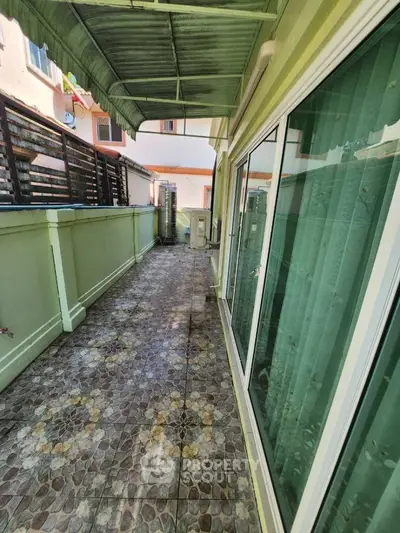 Spacious balcony with tiled flooring and glass sliding doors in a modern home.