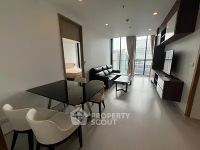 Modern living room with sleek furniture and city view from balcony in high-rise apartment.