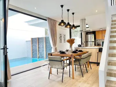 Modern open-plan kitchen and dining area with pool view, featuring elegant decor and natural light.