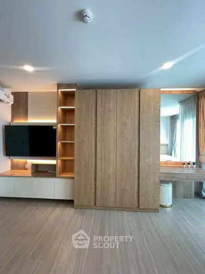 Modern living room with sleek wooden cabinetry and mounted TV, featuring elegant lighting and spacious design.