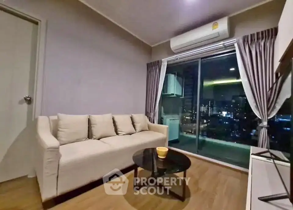 Modern living room with city view and balcony access, featuring cozy sofa and sleek decor.