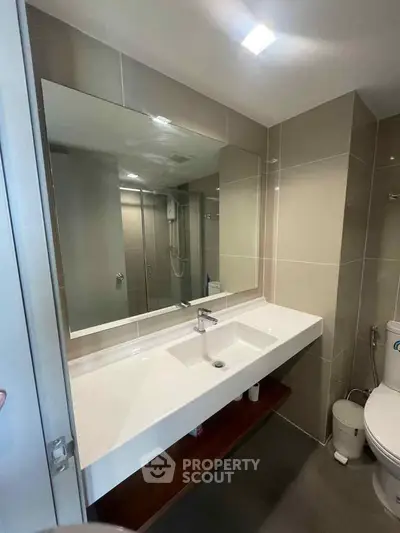 Modern bathroom with sleek sink and large mirror in contemporary apartment.