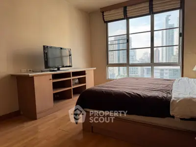Spacious bedroom with city view, featuring wooden furniture and large window.