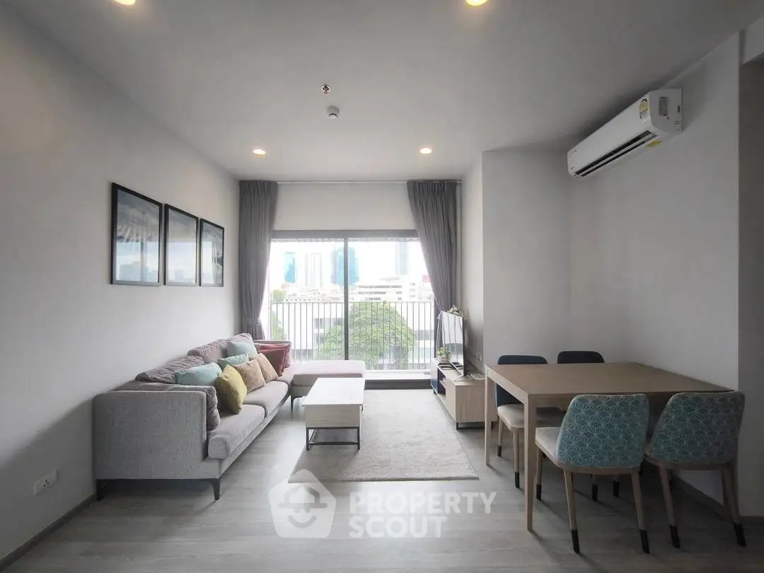 Modern living room with cozy sofa and dining area, featuring large window and stylish decor.