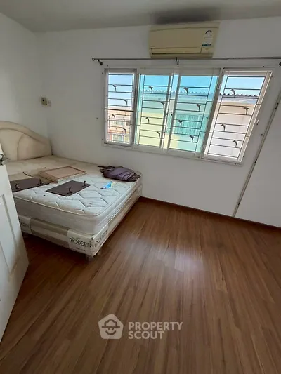 Spacious bedroom with wooden flooring and large windows offering natural light.