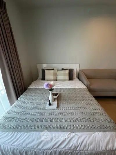 Cozy bedroom with stylish decor and natural light, featuring a comfortable bed and elegant sofa.