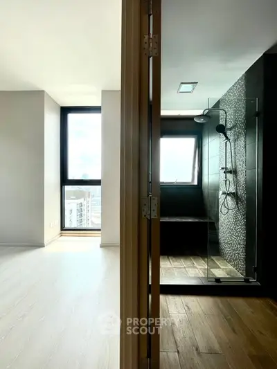Modern apartment with sleek shower and bright living area, featuring large windows and stylish flooring.