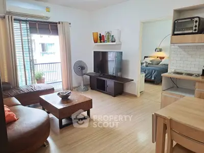 Modern living room with cozy seating and large TV, adjacent to a stylish bedroom.