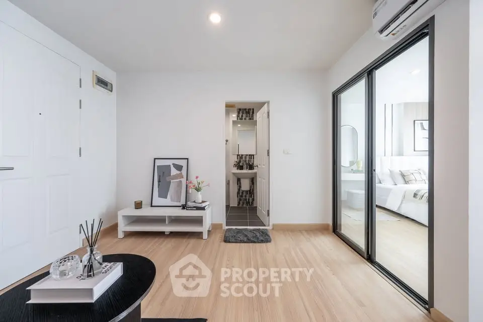 Modern apartment interior with wooden flooring, stylish decor, and a glimpse into a cozy bedroom.