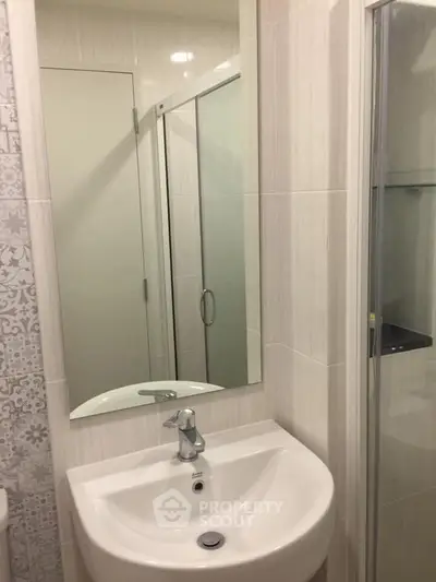 Modern bathroom with sleek sink and glass shower enclosure in stylish apartment.