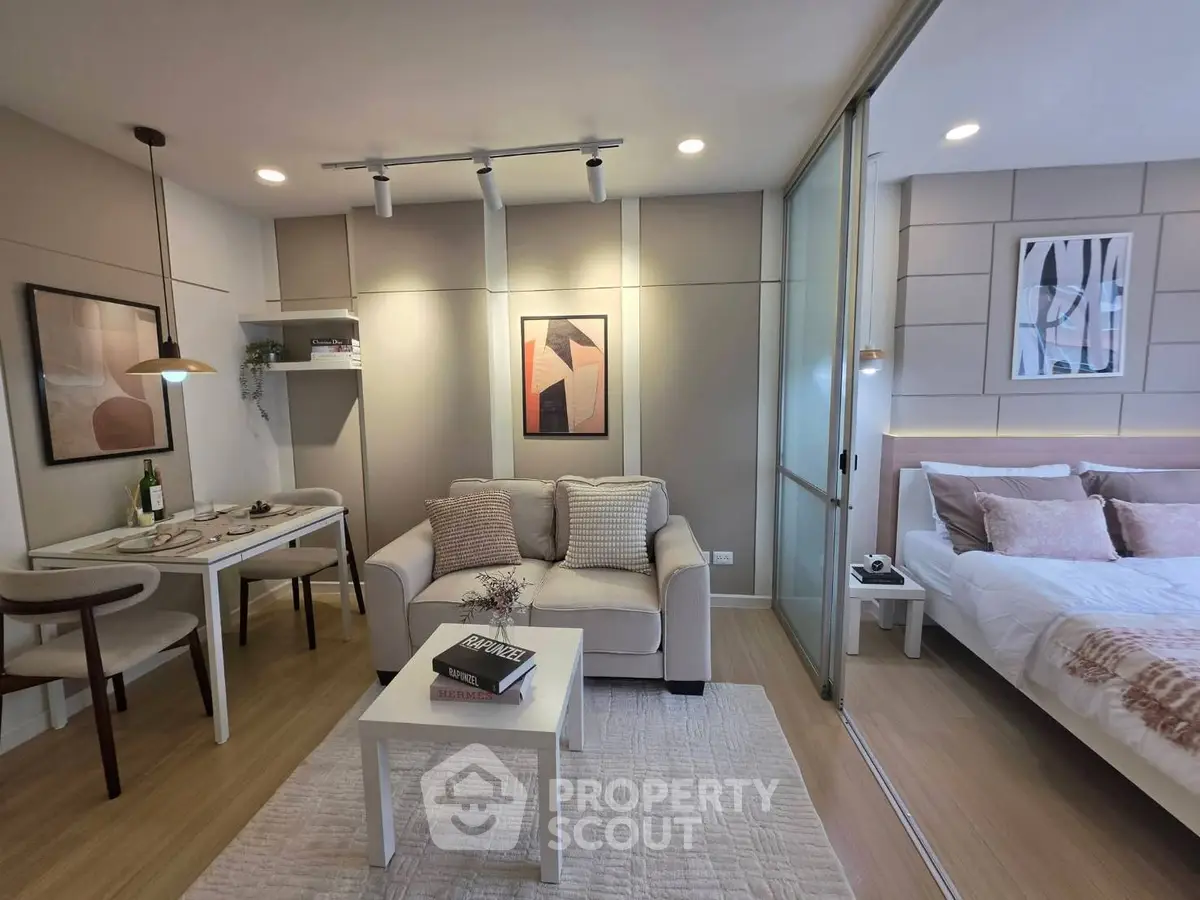 Modern studio apartment with cozy living area and stylish bedroom separated by glass partition.