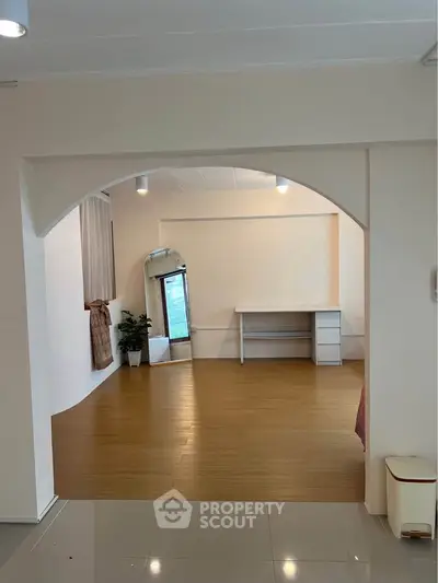Spacious interior with wooden flooring and archway, ideal for versatile living space.