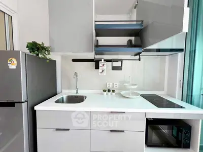 Modern kitchen with sleek cabinets, induction cooktop, and built-in microwave in a stylish apartment.