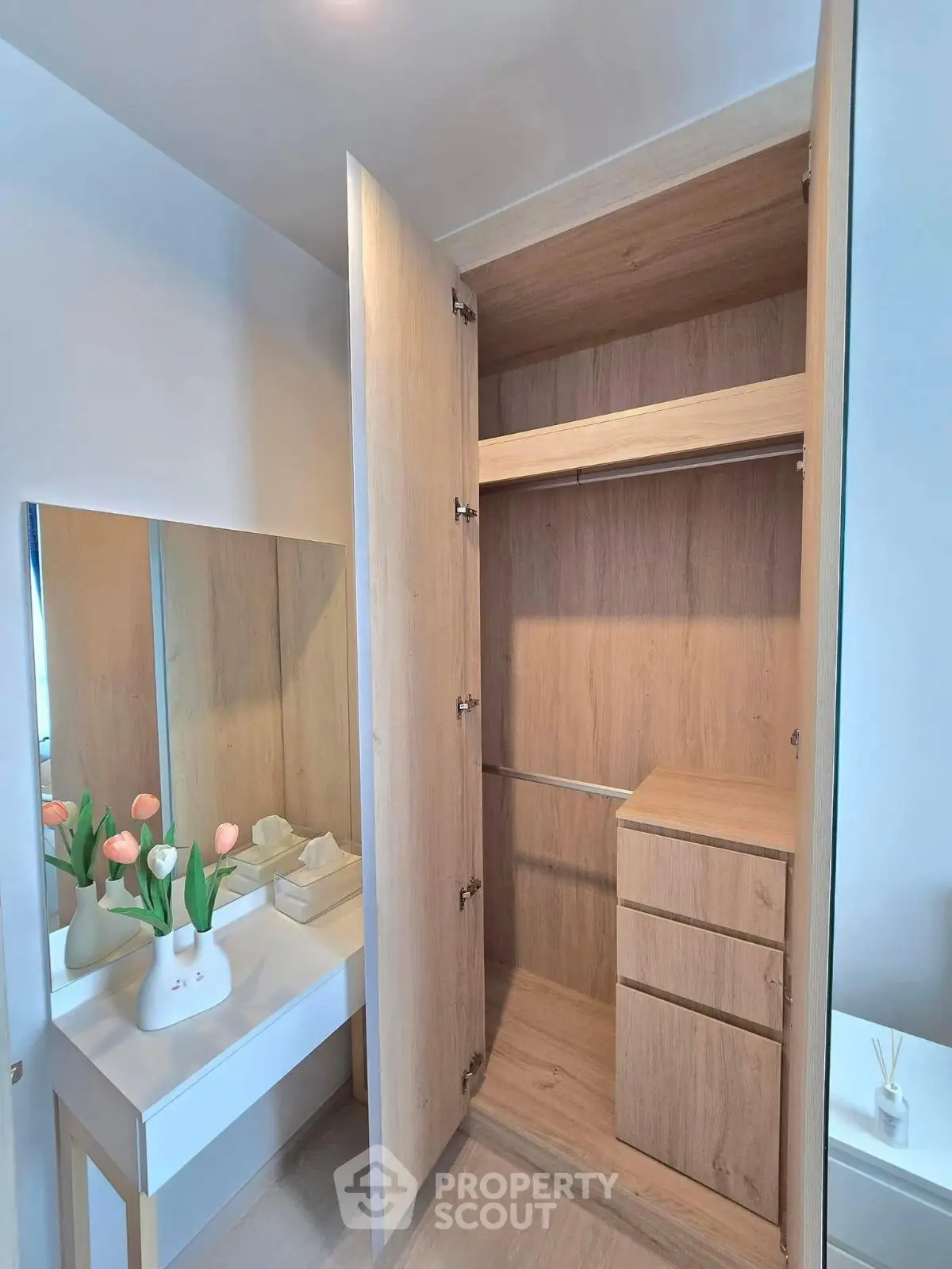Spacious wooden wardrobe with built-in drawers and adjacent vanity in modern bedroom.