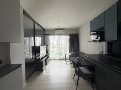 Modern living room with sleek furniture and large window offering natural light.