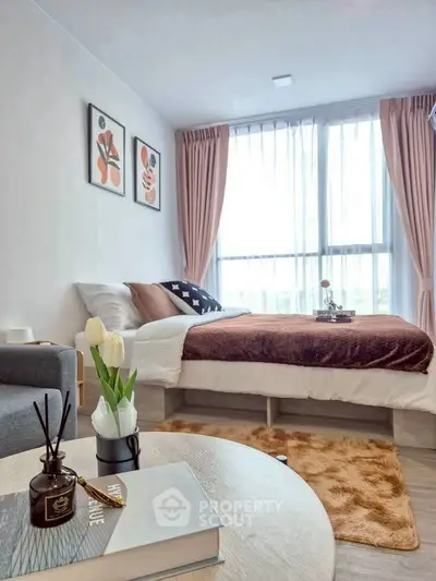 Cozy bedroom with modern decor, large window, and stylish furnishings in a bright apartment.