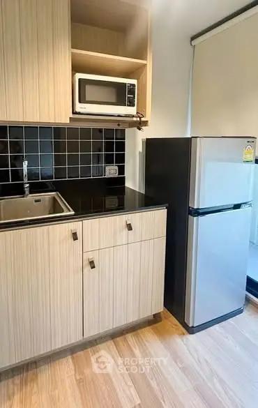 Modern kitchen with sleek cabinetry, microwave, and stainless steel fridge