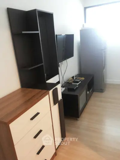 Modern living room with sleek furniture and flat-screen TV, featuring a stylish storage unit and wooden flooring.