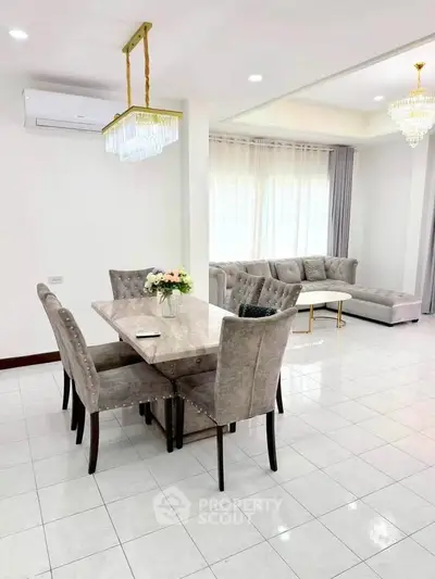 Elegant living room with plush seating and dining area, featuring modern chandeliers and ample natural light.