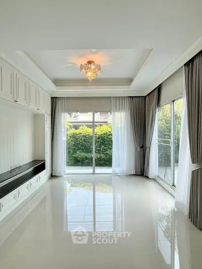 Elegant living room with chandelier and large windows overlooking garden