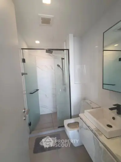 Modern bathroom with glass shower and sleek fixtures in contemporary apartment.