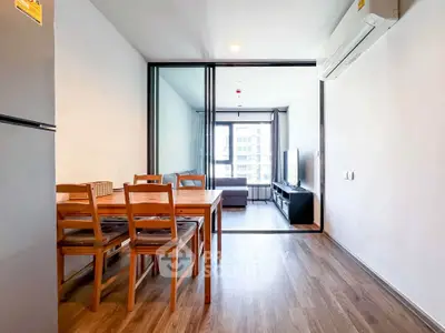 Modern apartment with open layout dining and living area, featuring sleek furniture and natural light.