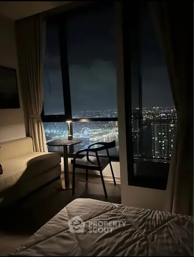 Luxurious bedroom with stunning city view from high-rise window at night.