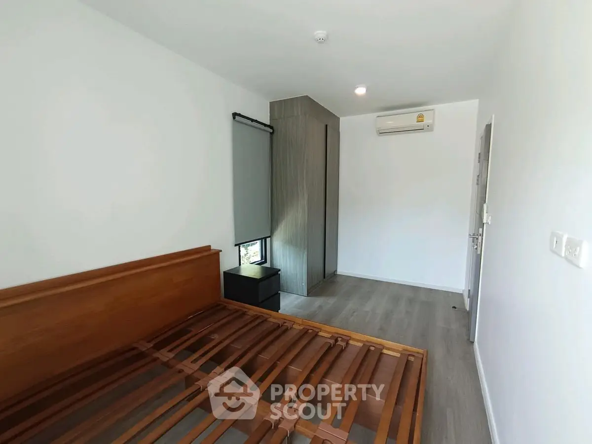 Spacious bedroom with modern design and air conditioning unit, featuring a wooden bed frame and sleek flooring.
