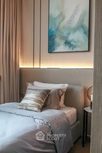 Cozy bedroom with modern decor and ambient lighting, featuring a stylish painting above the bed.