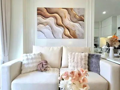 Elegant living room with plush white sofa, abstract wall art, and modern decor accents.