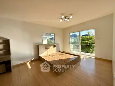 Spacious bedroom with modern design and large window offering natural light and scenic view.