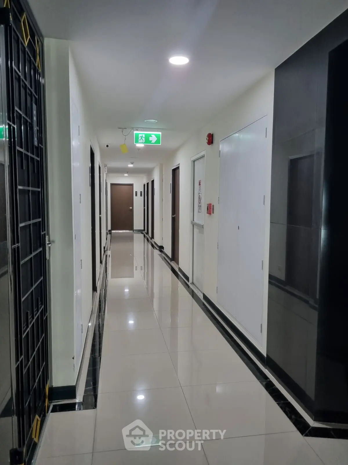Modern apartment hallway with glossy tiles and emergency exit sign