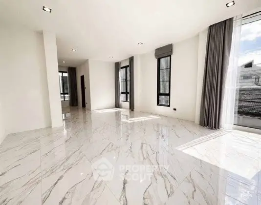 Spacious modern living room with marble flooring and large windows offering abundant natural light.