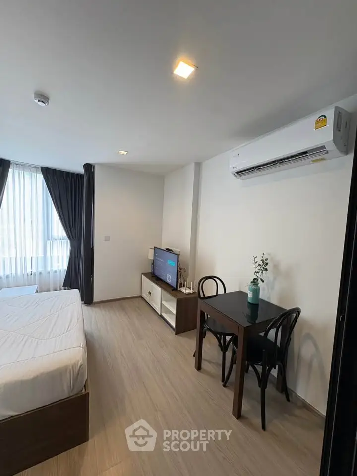 Modern studio apartment with cozy bedroom and dining area, featuring sleek furniture and natural light.