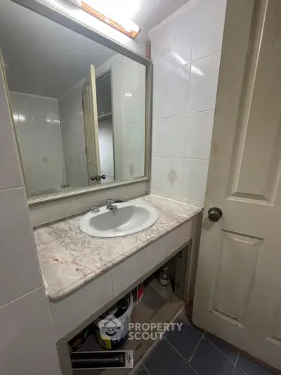 Compact bathroom with marble countertop and large mirror in cozy apartment.
