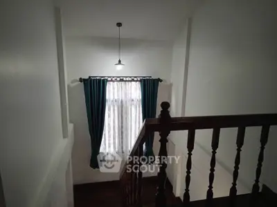Charming staircase with elegant wooden railing and stylish curtains, perfect for a cozy home ambiance.
