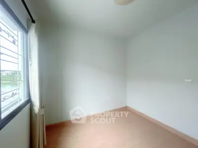 Spacious empty room with large window and natural light, perfect for customization.