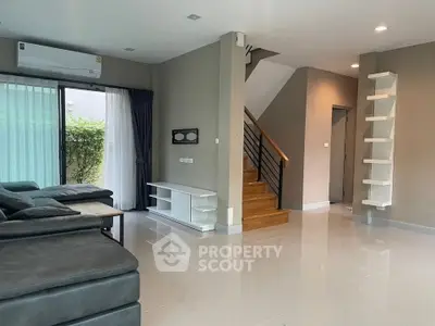Spacious modern living room with sleek staircase and large windows for natural light.