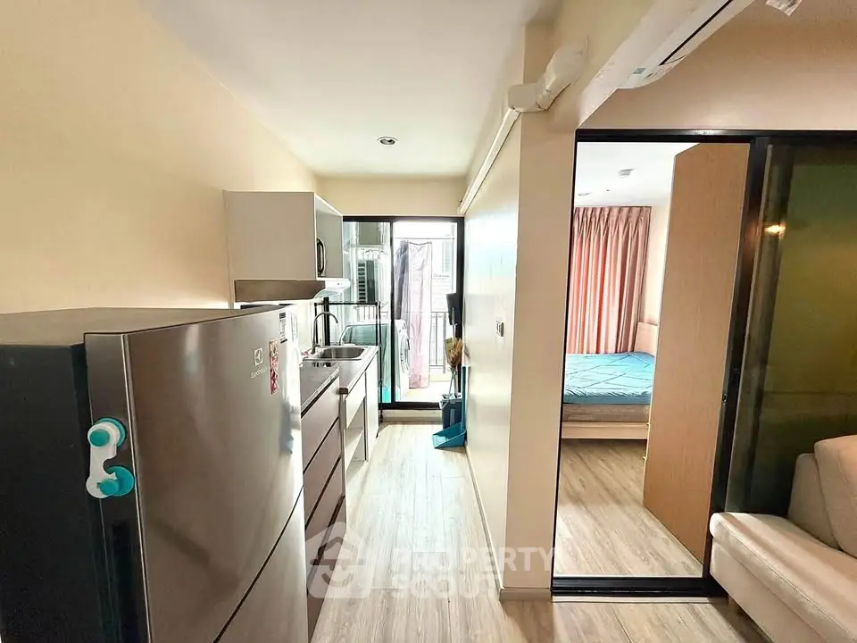 Modern apartment kitchen with sleek appliances and cozy bedroom view