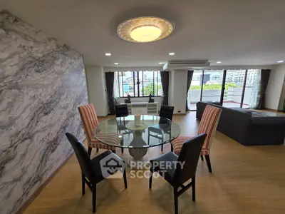 Spacious living room with elegant dining area and large windows offering city views.